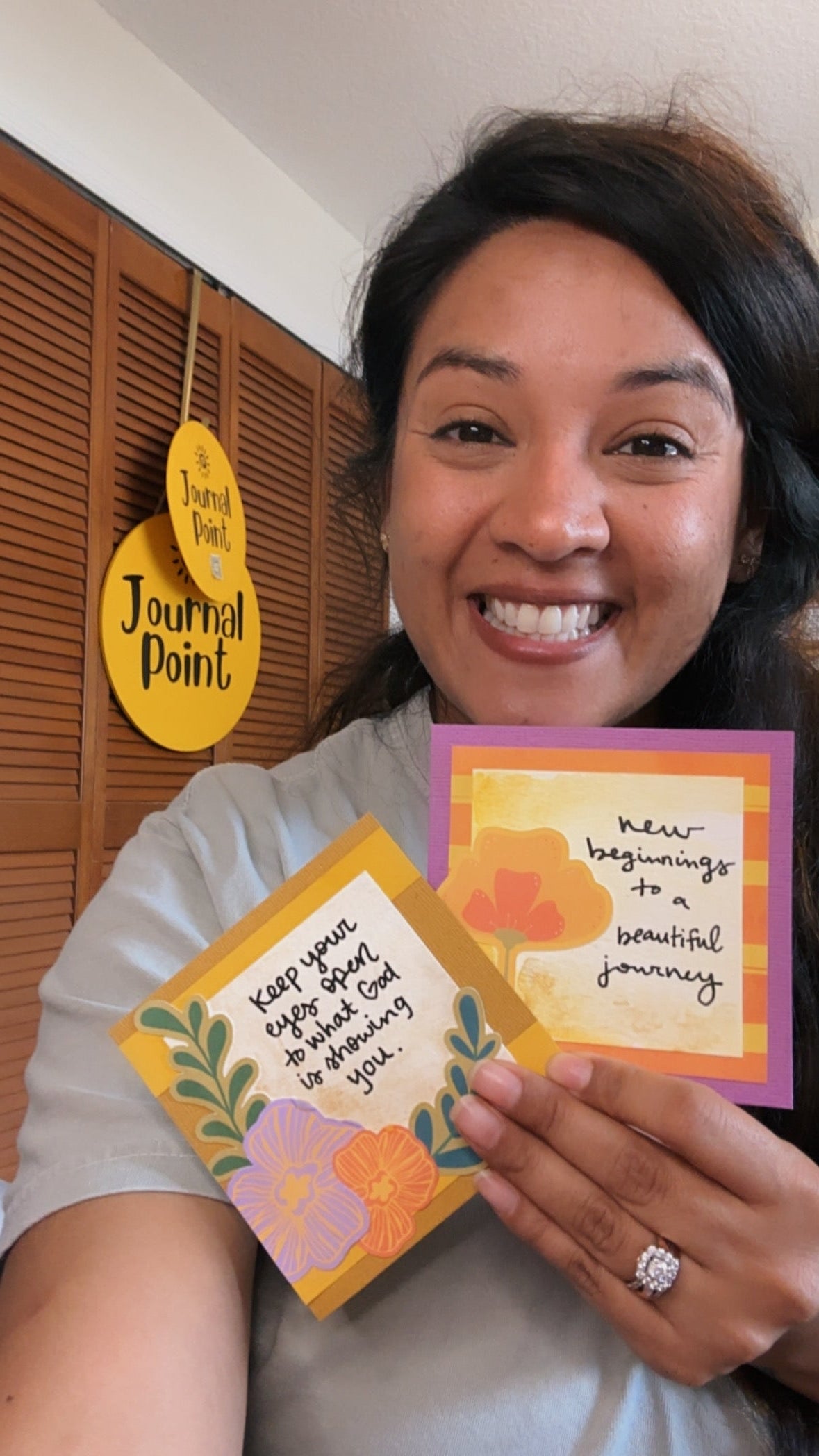 Woman holding two colorful cards with text and a yellow circular sign in the background.