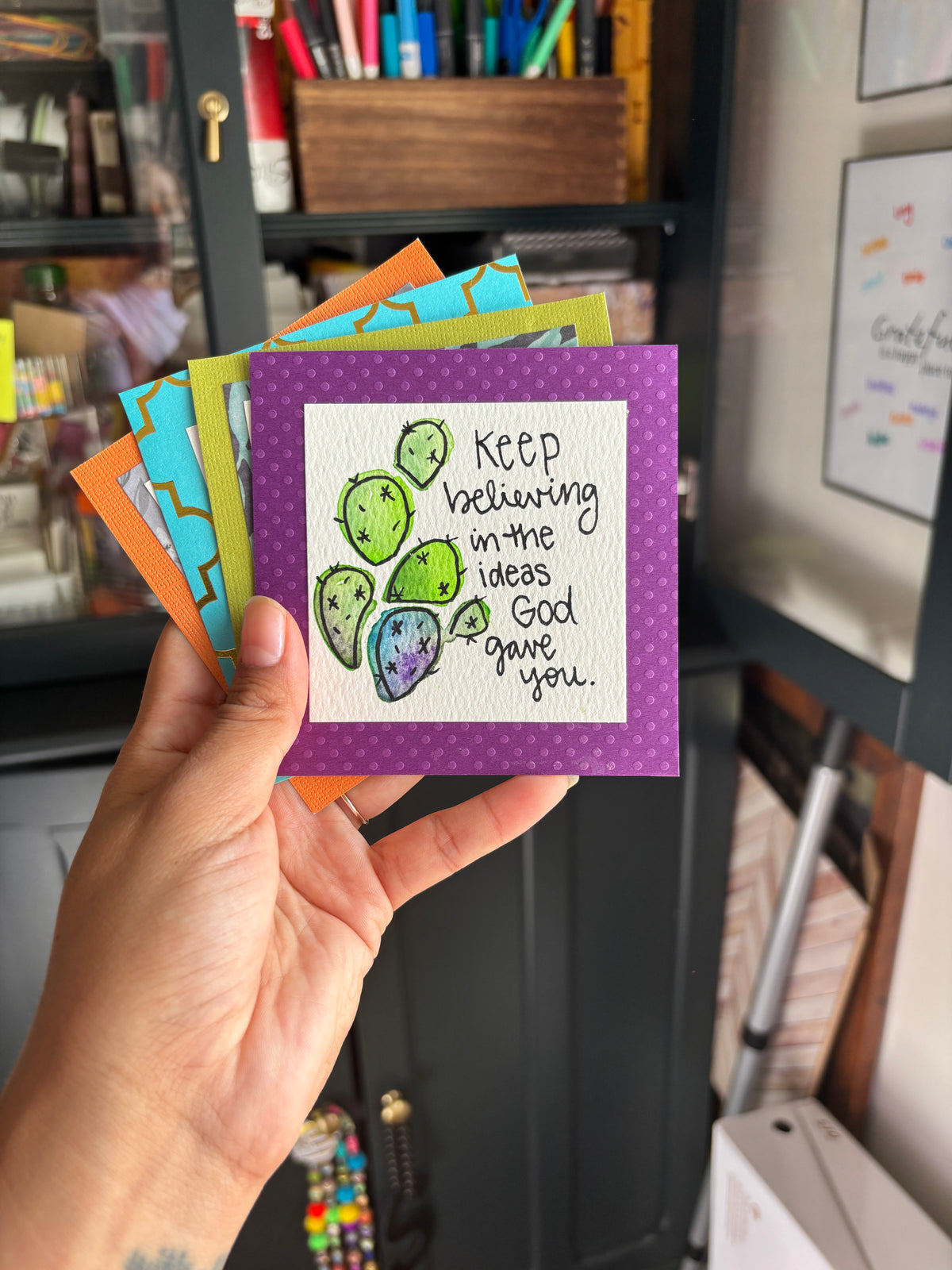 Hand holding a bunch of mini inspirational artworks