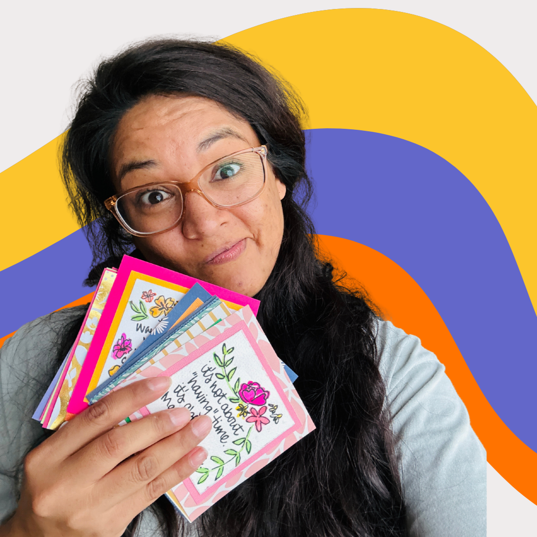 Owner, Amanda, holding colorful mini paintings against a vibrant, abstract background